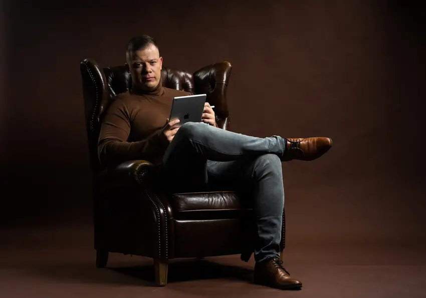 Homme qui lit dans un fauteuil en cuir