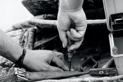 Gros plan sur les mains d'un artisan au travail sur le dossier d'un fauteuil club 