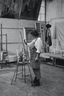 photo en noir et blanc artiste qui peint une toile dans son atelier