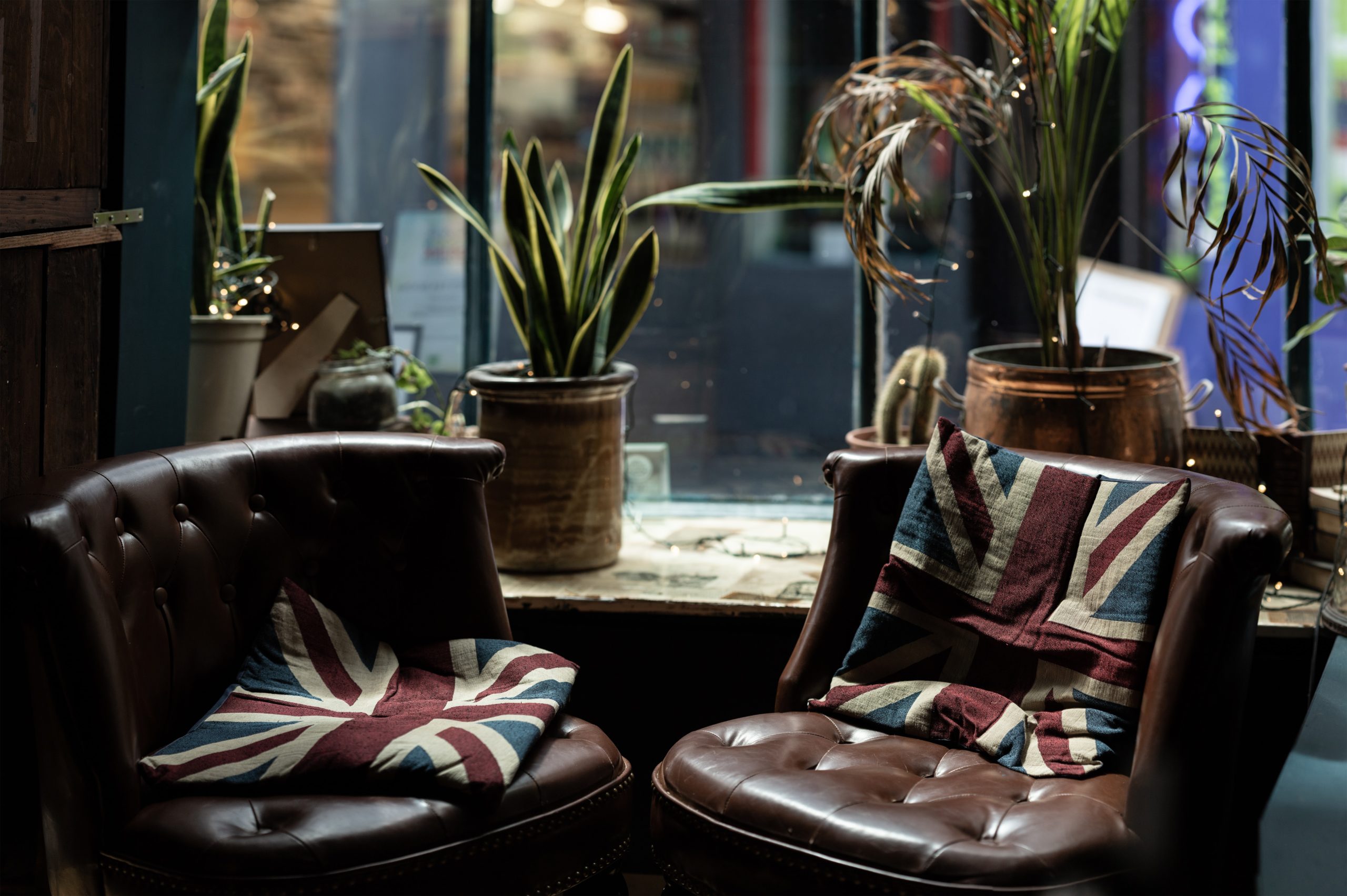 Vitrine d'un salon avec 2 fauteuils club sur lesquels sont posés des coussins avec le drapeau du Royaume Uni